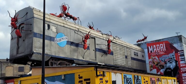 old railway carriage on roof of cafe with giant ant sculptures on it